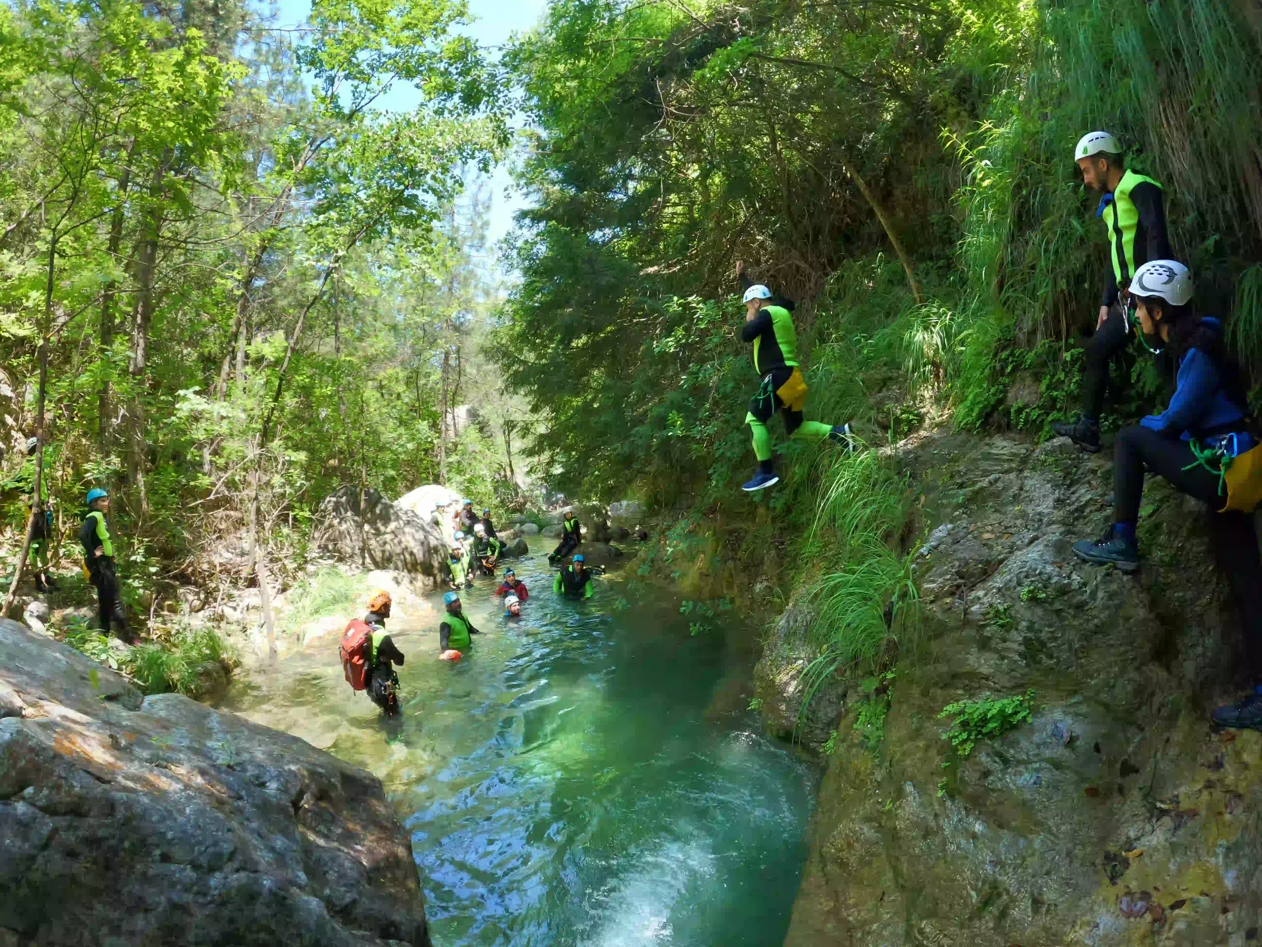Adventure seeker jumping into a crystal clear emerald pool during a canyoning tour in Orlias stream on Mount Olympus